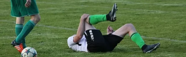 football player in pain holding knee